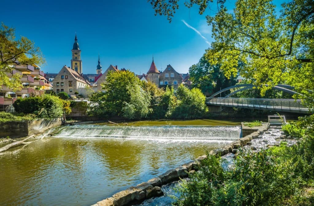Blick über die Jagst auf die Altstadt von Crailsheim mit Johanneskirche und moderner Fußgängerbrücke